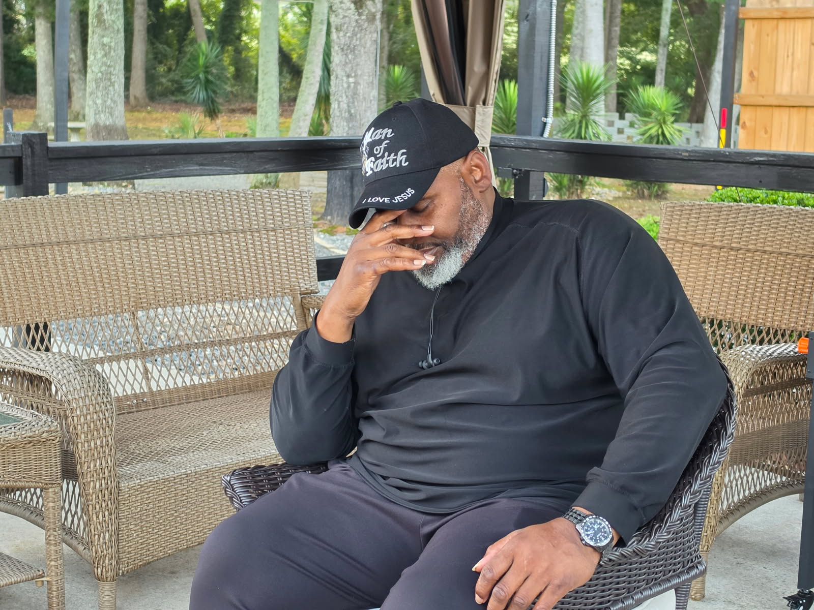 A veteran sitting outdoors in a quiet moment of reflection, hand to his face